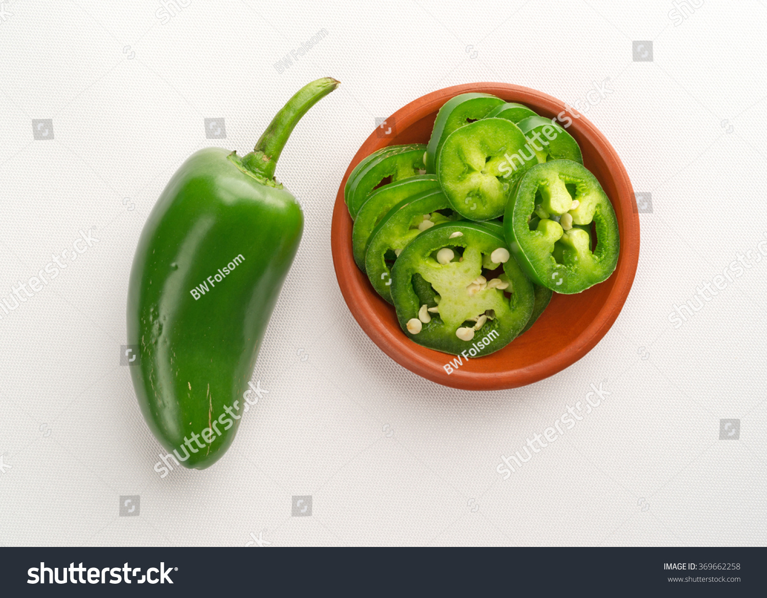 top view of a small bowl of sliced jalapeno peppers plus a large